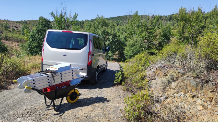Con la furgoneta y una carretilla trasnsportamos las herramientas de instalación al bosque Una furgoneta y una carretilla con una escalera frente al bosque de la colonia de murciélagos